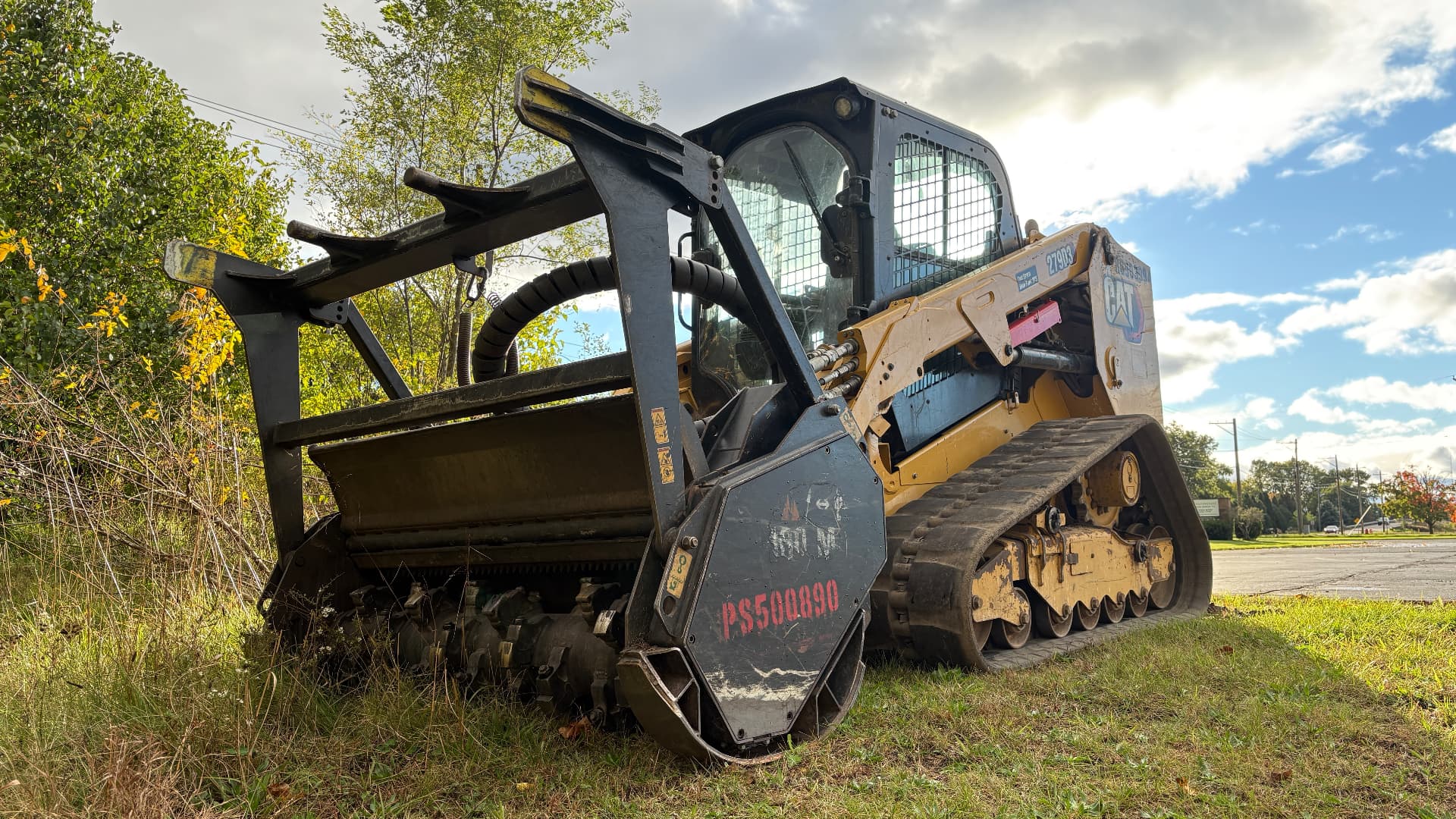 Cat tracked loader with forestry mulcher attachment at the edge of a wooded property