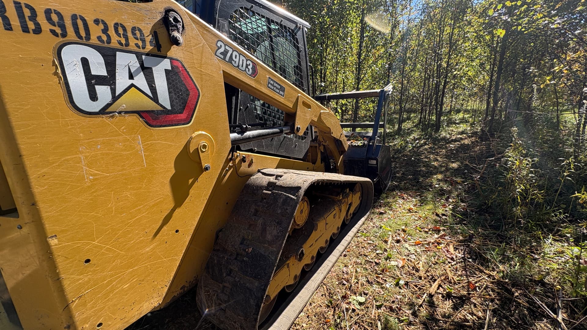 Cat tracked loader working along a wooded access trail